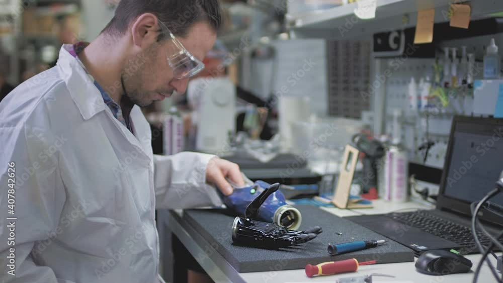 A scientist engineer creates or diagnoses a robotic arm prosthesis. Prosthetic laboratory, industrial production. A mechanical arm for a fulfilling life. Creation of cybernetic limbs. Helping amputees A scientist engineer creates or diagnoses a robotic arm prosthesis. Prosthetic laboratory, industrial production. A mechanical arm for a fulfilling life. Creation of cybernetic limbs. Helping amputees