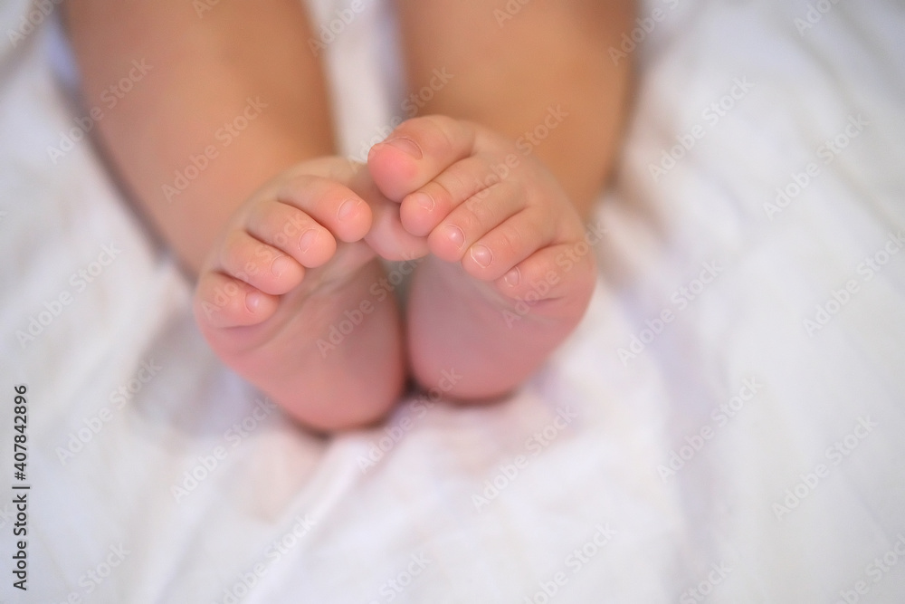 Tiny baby feet on white. Fingers folded in the shape of a heart Tiny baby feet on white. Fingers folded in the shape of a heart