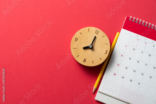 close up of calendar and alarm clock on the red table background, planning for business meeting or travel planning concept photo
