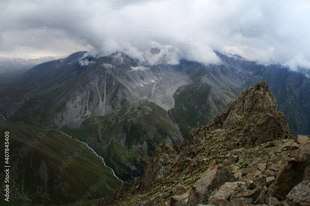 Alpine gorge and peak with a rock in the foreground in summer in bad weather, Prokhodnoye gorge, Tien shan, Kazakhstan
