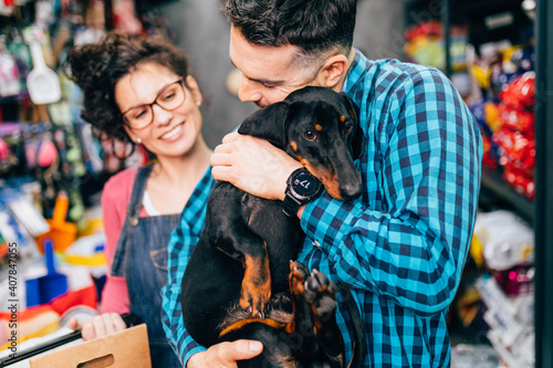 Happy couple buying toys and food for their Dachshund in pet shop. © hedgehog94