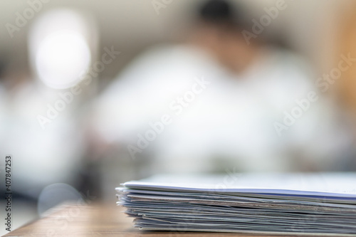 Exam answer sheet pile, blurry application document paperwork stack on office work table in examination room or classroom with blur education background school class university students taking test photo