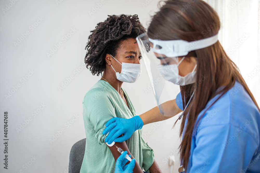 Side view shot of female nurse wearing protective mask and gloves preparing medical syringe for giving injection to patient. Corona Virus Immunization Side view shot of female nurse wearing protective mask and gloves preparing medical syringe for giving injection to patient. Corona Virus Immunization