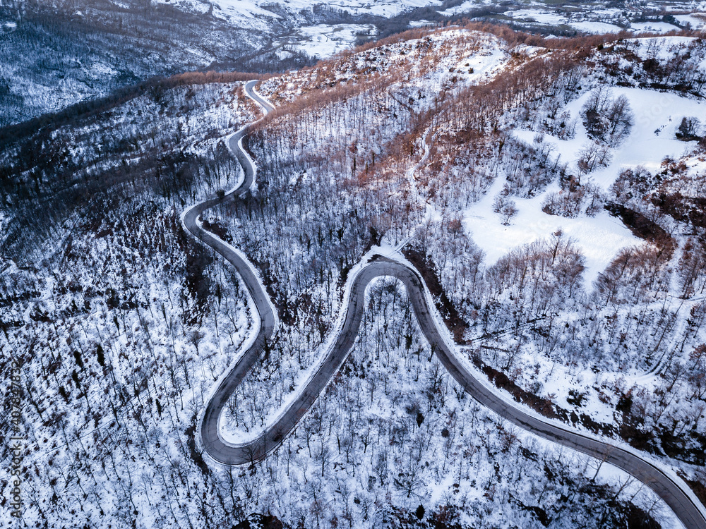 Road with curves and hairpin bends in a snowy forest