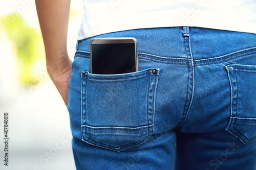 Close-up portrait of a smartphone in the back pocket of a girl's jeans.