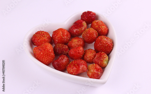 Red strawberries in a plate in the shape of a heart 