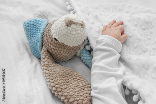 children's hand hugs a toy. Amigurumi. Sleeping with toy