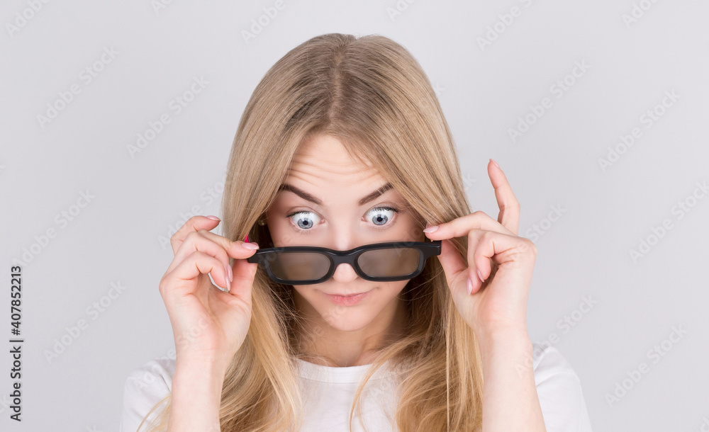 Young woman with glasses is very surprised looking down and lowering her glasses. Surprise and shopping concept on white background. Young woman with glasses is very surprised looking down and lowering her glasses. Surprise and shopping concept on white background.