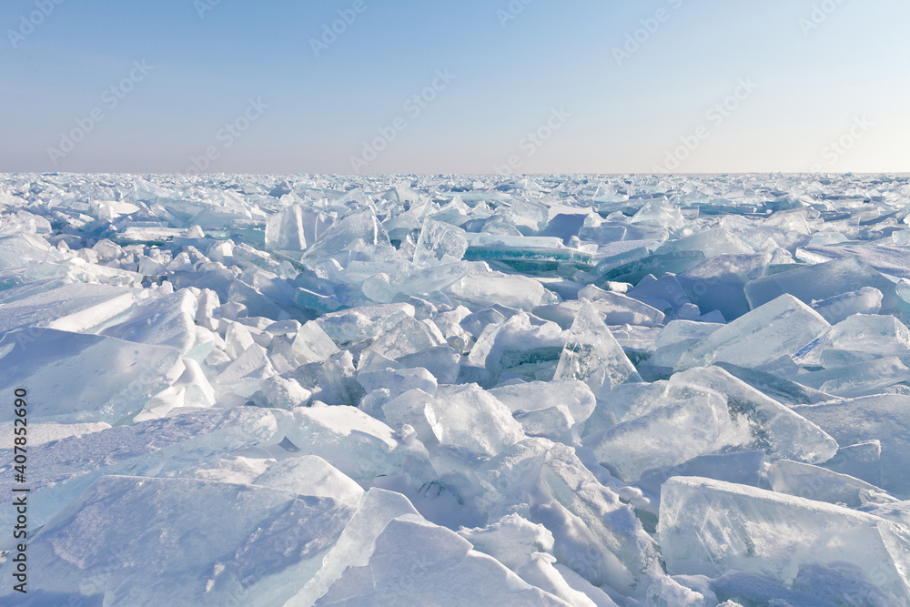 Fototapeta premium Endless hummock field on the frozen Lake Baikal. Piles of snow-covered debris of blue ice on a sunny frosty day. Cold natural background. Unusual winter landscape