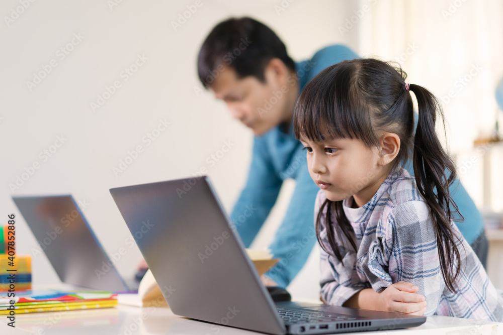 Asian daughter to studying the lesson of online class nearly with working father, concept of role of parent to supporting the child homeschooling during stay home and quarantine in virus outbreak. Asian daughter to studying the lesson of online class nearly with working father, concept of role of parent to supporting the child homeschooling during stay home and quarantine in virus outbreak.