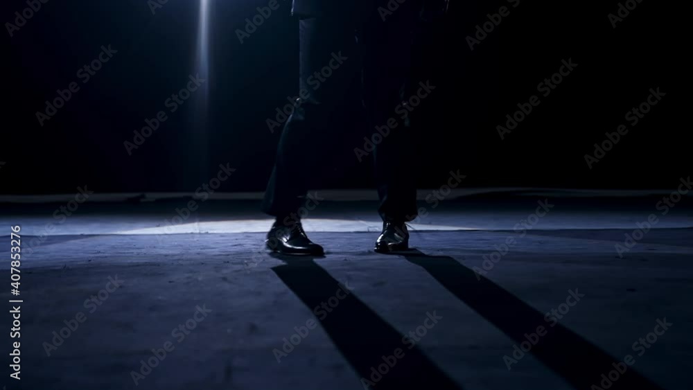 Legs of a dancer in move. Man in trousers and shoes dancing on the stage in dark scenic light. Legs of a dancer in move. Man in trousers and shoes dancing on the stage in dark scenic light.