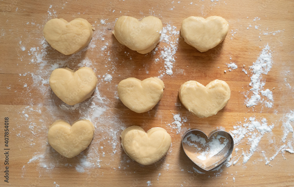 The heart cookies cutter and the doughs on the wooden cutting board. Valentine's day baking concept.Homemade bakery with love.