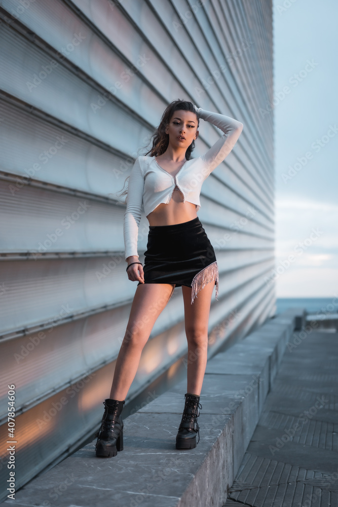 Fashion photoshoot with a brunette girl in the city at blue hour next to a gray building Fashion photoshoot with a brunette girl in the city at blue hour next to a gray building