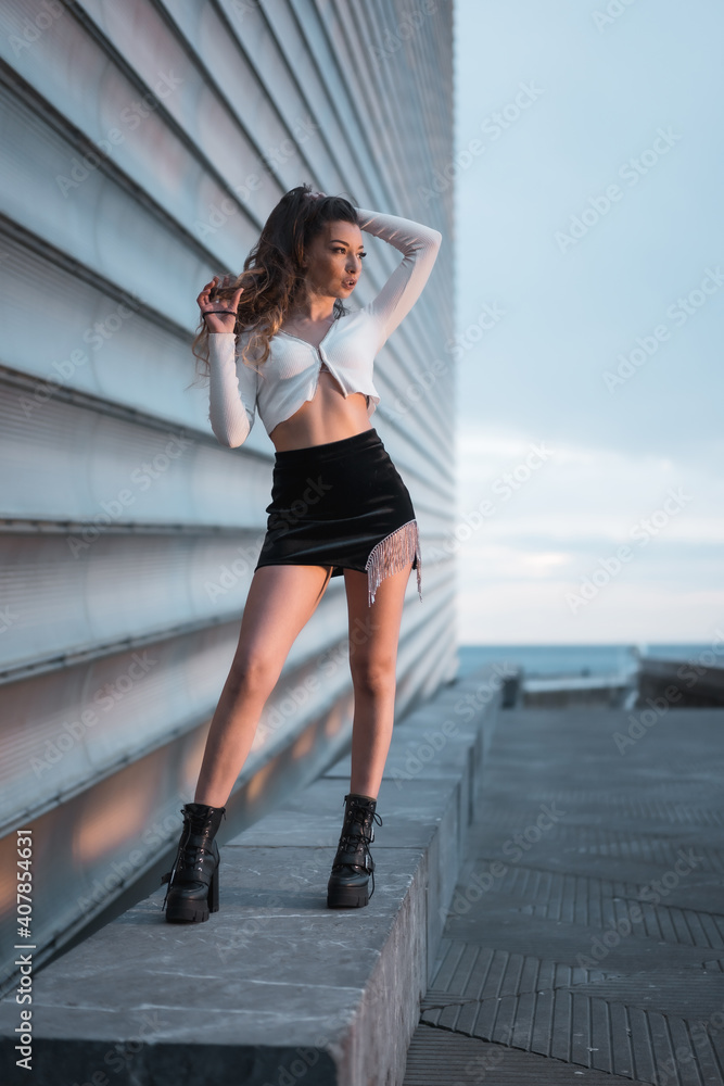 Fashion photoshoot with a brunette girl in the city at blue hour next to a gray building Fashion photoshoot with a brunette girl in the city at blue hour next to a gray building