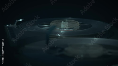 
Macro shots of a 1970s quarter-inch open-reel tape recorder in operation. Shallow depth of field with focus on the rotating spools. Suggestive of a wiretap or surveillance.  photo