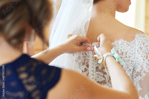 the bride's mother fastens the pearl buttons on the wedding dress. preparation for the ceremony, the morning of the bride