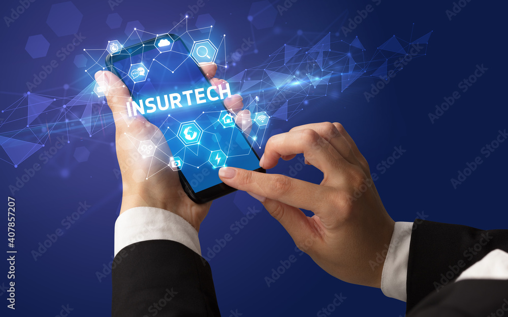 Female hand holding smartphone with INSURTECH inscription, modern technology concept Female hand holding smartphone with INSURTECH inscription, modern technology concept