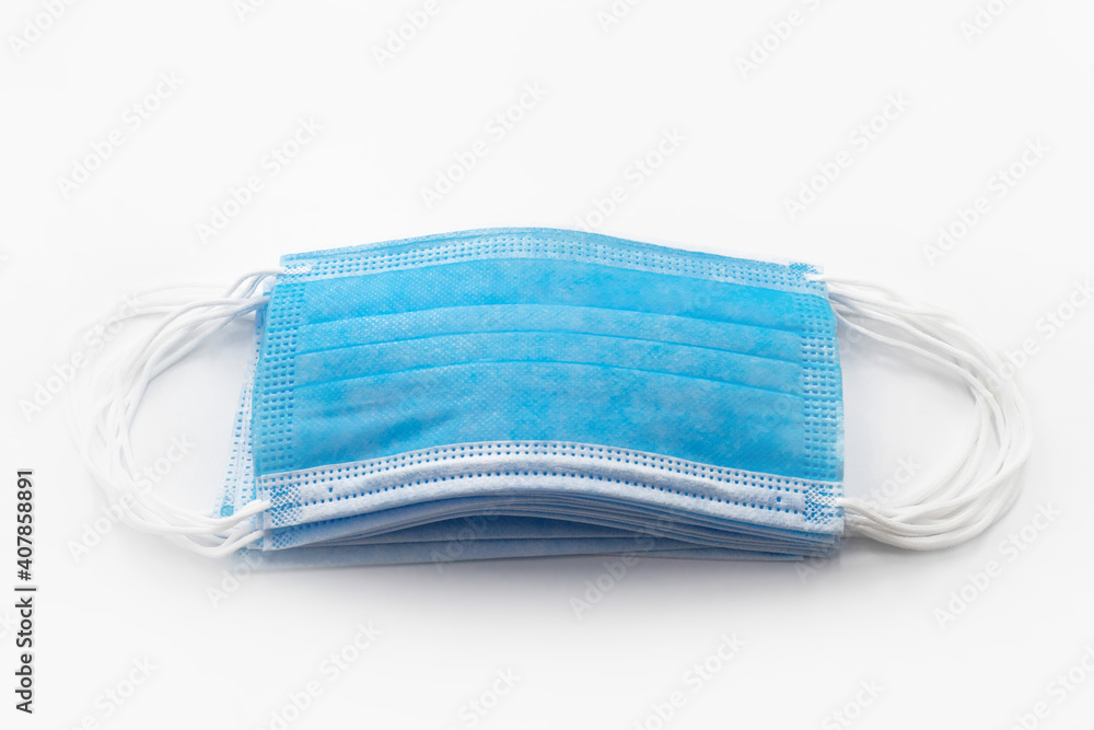 A small number of blue surgical masks are placed in the center on a white background A small number of blue surgical masks are placed in the center on a white background