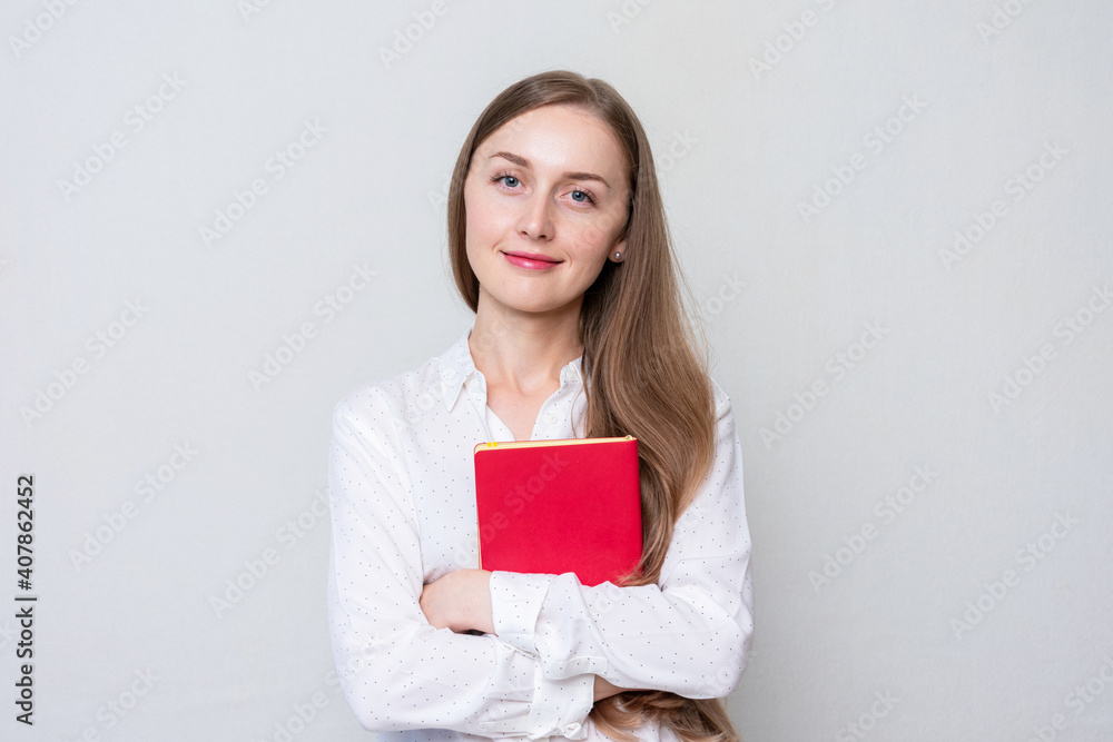 Smiling girl student with red textbook. Concept of education. Portrait, white background, copy space Smiling girl student with red textbook. Concept of education. Portrait, white background, copy space