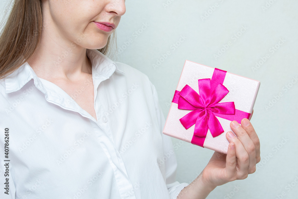 Disaffected woman with pink gift in hands, cropped image, close up Disaffected woman with pink gift in hands, cropped image, close up