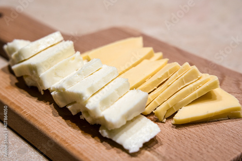 Cheese cut and ready to serve on wooden cutting board.