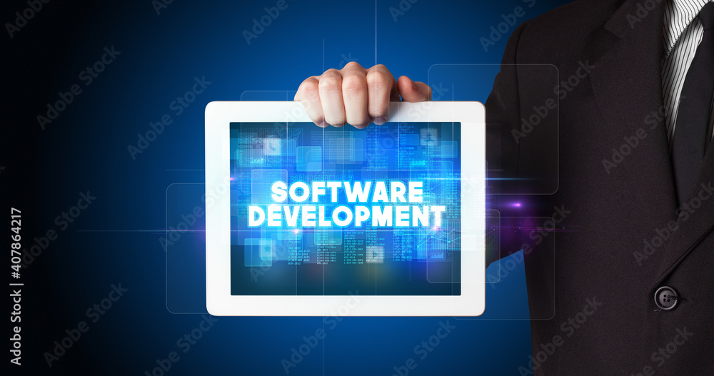 Young business person working on tablet and shows the inscription: SOFTWARE DEVELOPMENT Young business person working on tablet and shows the inscription: SOFTWARE DEVELOPMENT