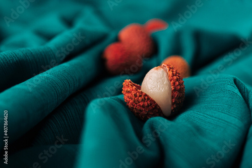 Closeup aesthetic of fresh organic Lychee (Litchi fruit) against dark cyan cloth background. Concept healthy food, diet, vegan