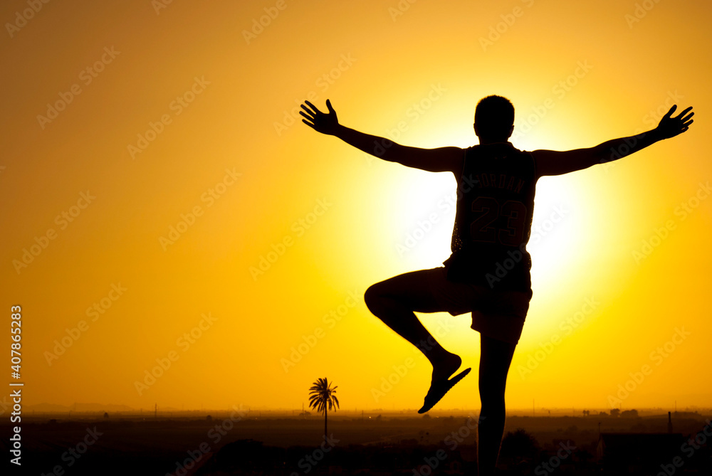 silhouette of a man on the mountain watching the sunset with open arms silhouette of a man on the mountain watching the sunset with open arms