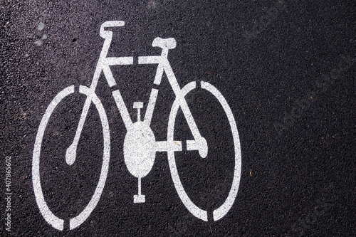 Bicycle path made of asphalt and a painted sign in the shape of a bicycle