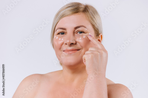 Senior blonde woman with cream mask under the eyes. Beautiful woman with perfect skin and cream contour anti-aging and wrinkle eyes. Concept of beauty and perfection