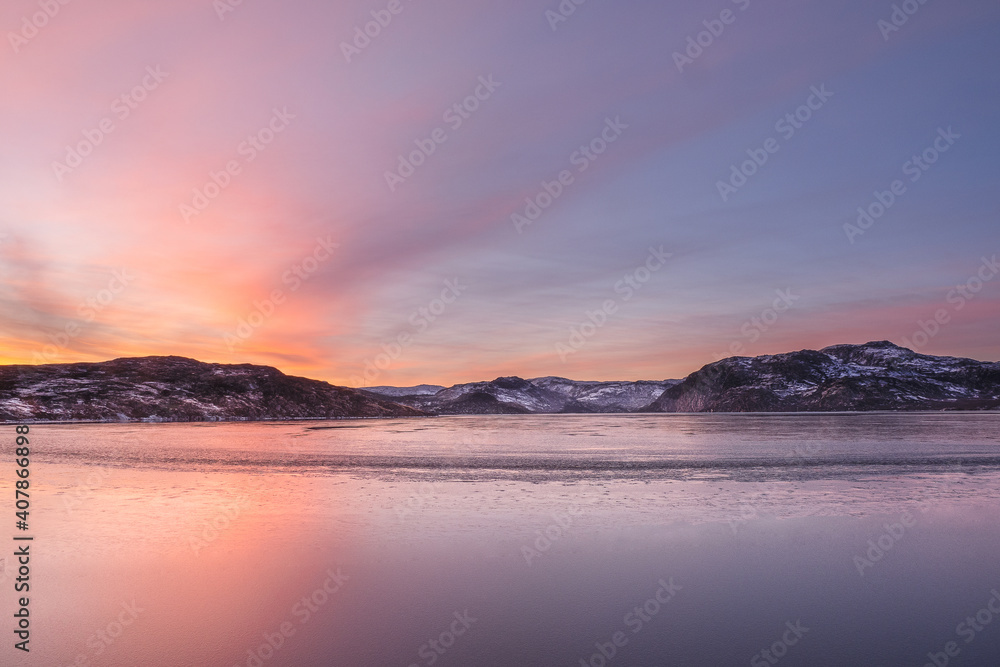 Natural sunset background. An ice-covered mountain lake. Magic Magenta sunset on a mountain North of the lake.