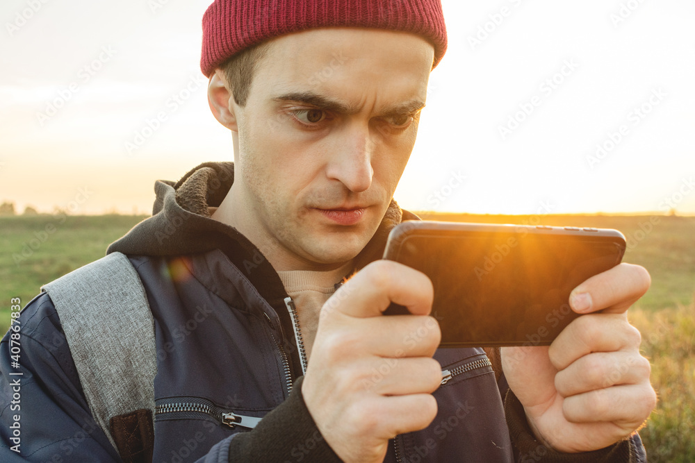 Focused person plays mobile games on the phone against the background of a beautiful landscape, portrait, toned Focused person plays mobile games on the phone against the background of a beautiful landscape, portrait, toned