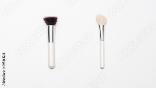 Two makeup brushes on a white background  copy space  advertising  slogan  text  top view  16 9