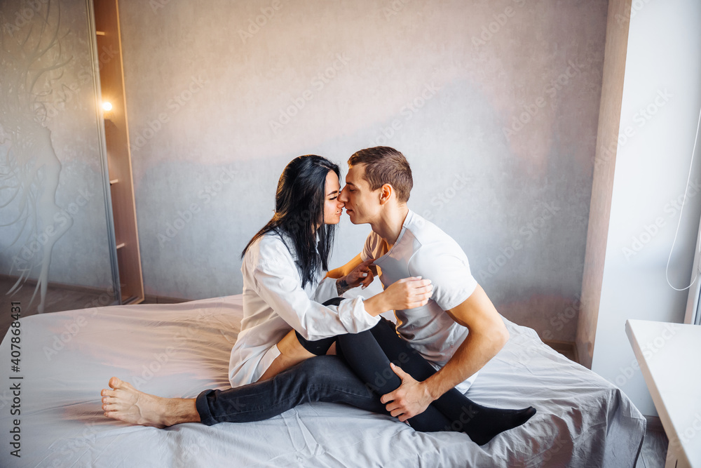 Beautiful passionate couple having sex on the bed. Cheerful romantic lovers hugging. The