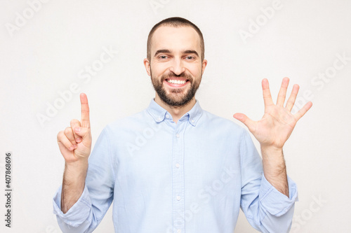 Bearded man shows fingers six, white background, copy space © Анастасия Семашко