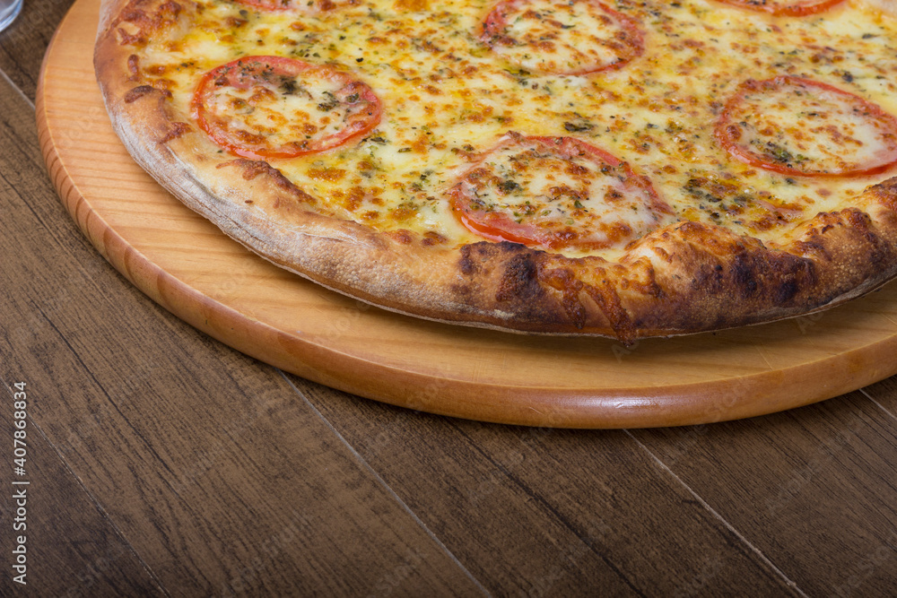 Mozzarella cheese pizza with red tomato slices on a wooden board. Close-up photography. Bottom space for texts.