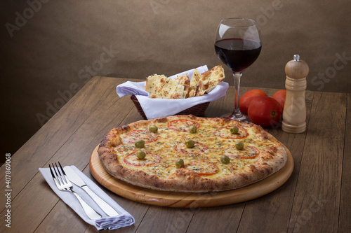 ricardo fernando franca junior pizza mussarela muçarela mucarelGourmet photo of Mozzarella cheese pizza with slices of red tomatoes and green olives. Glass of red wine. Fork and knife on the left 