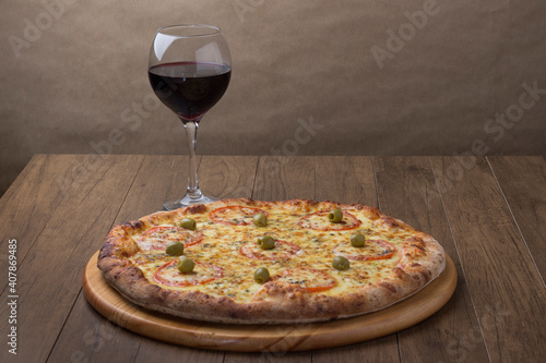 ricardo fernando franca junior pizza mussarela muçarela mucarelDelicious mozzarella cheese pizza with sliced ​​red tomatoes. A glass of red wine to accompany the meal. Horizontal photography 