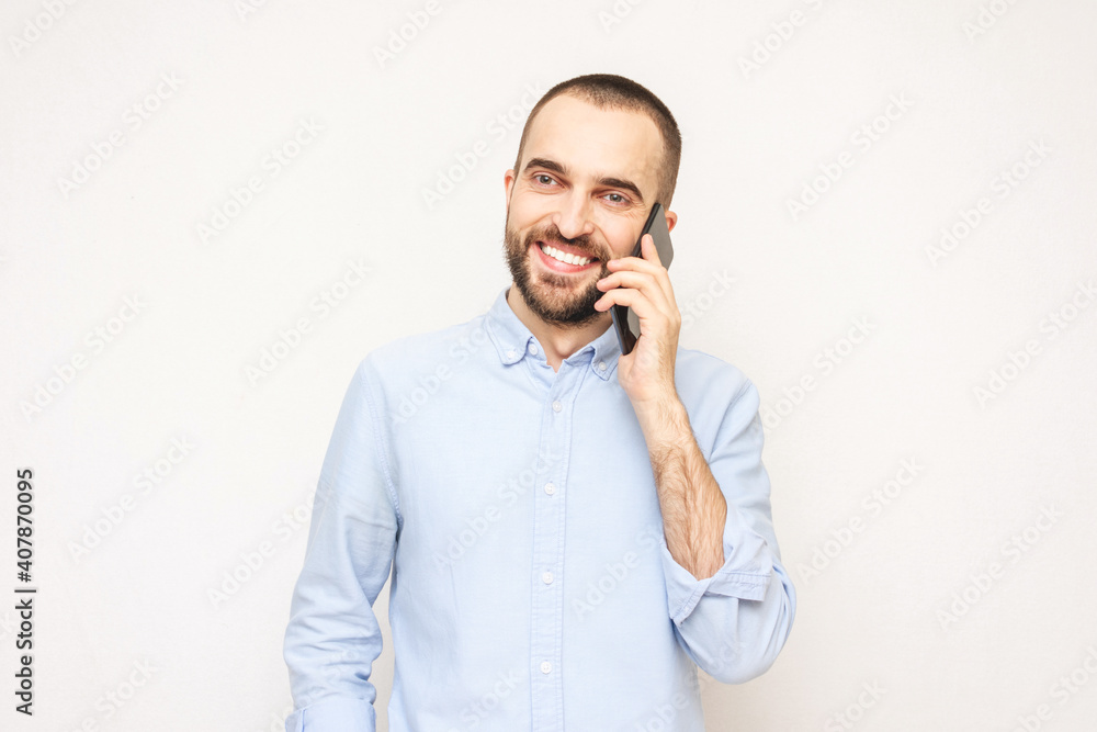 Smiling young man talking on mobile phone, white background, copy space Smiling young man talking on mobile phone, white background, copy space