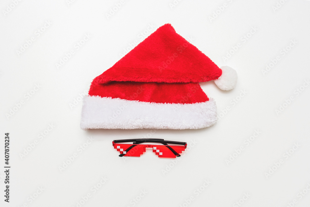 Red Santa hat and pixel glasses in white background, copy space, top view Red Santa hat and pixel glasses in white background, copy space, top view