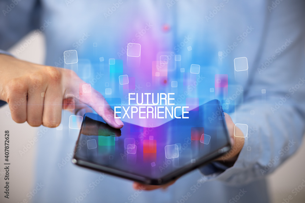 Young man holding a foldable smartphone with FUTURE EXPERIENCE inscription, educational concept Young man holding a foldable smartphone with FUTURE EXPERIENCE inscription, educational concept