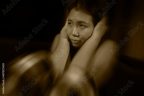 Asian woman suffering depression - dramatic artistic portrait of young beautiful sad and depressed Korean girl in pain helpless on couch at home in the dark