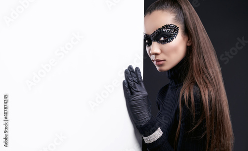 Fotografie, Obraz Elegant brunette woman in sequins mask posing near white wall