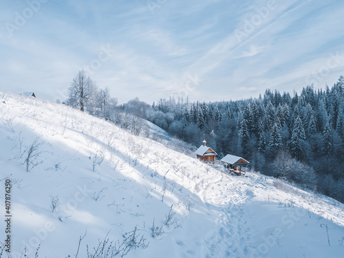 Holy spring with metal bowl and wooden house with plunge font pool for ablutions, gazebo for relaxing in a natural park in sunny winter day.