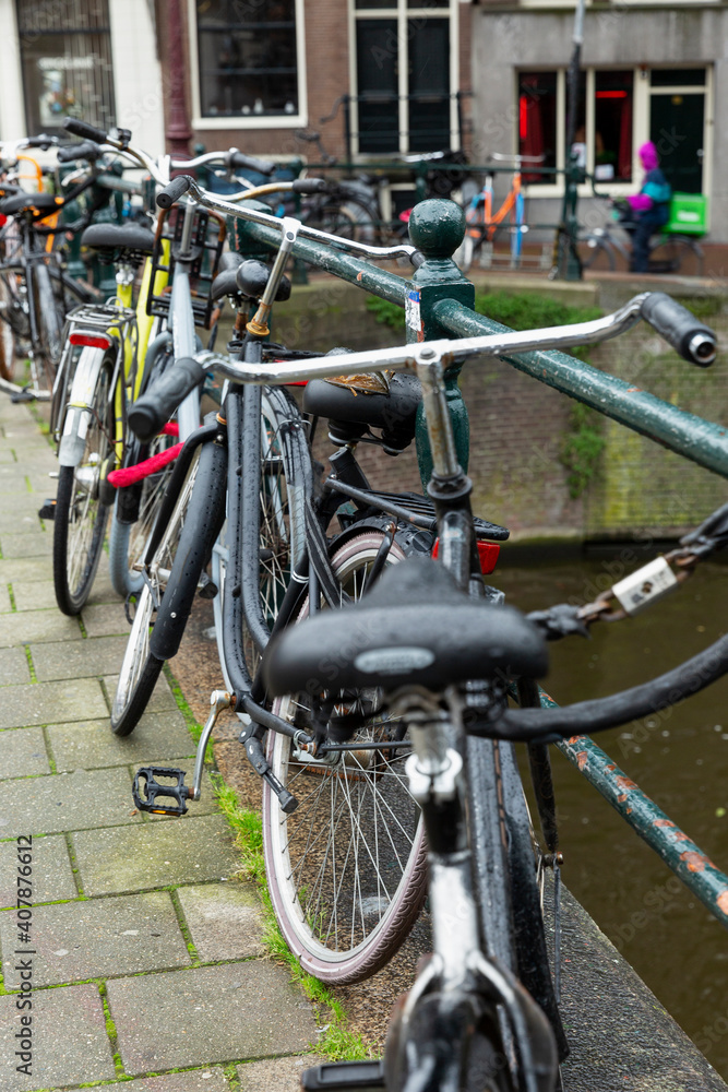 Obraz premium Parked bicycles on the canal in Amsterdam. Vertical.