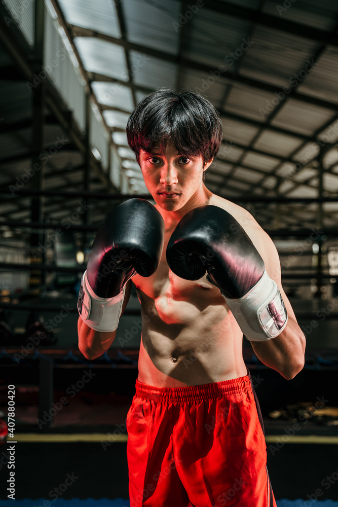 muscular young man stand wearing boxing gloves in the arena
