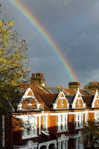London, England - A double rainbow appearing to end behind a row of typical English terraced houses, against a stormy grey sky.  Image has copy space.