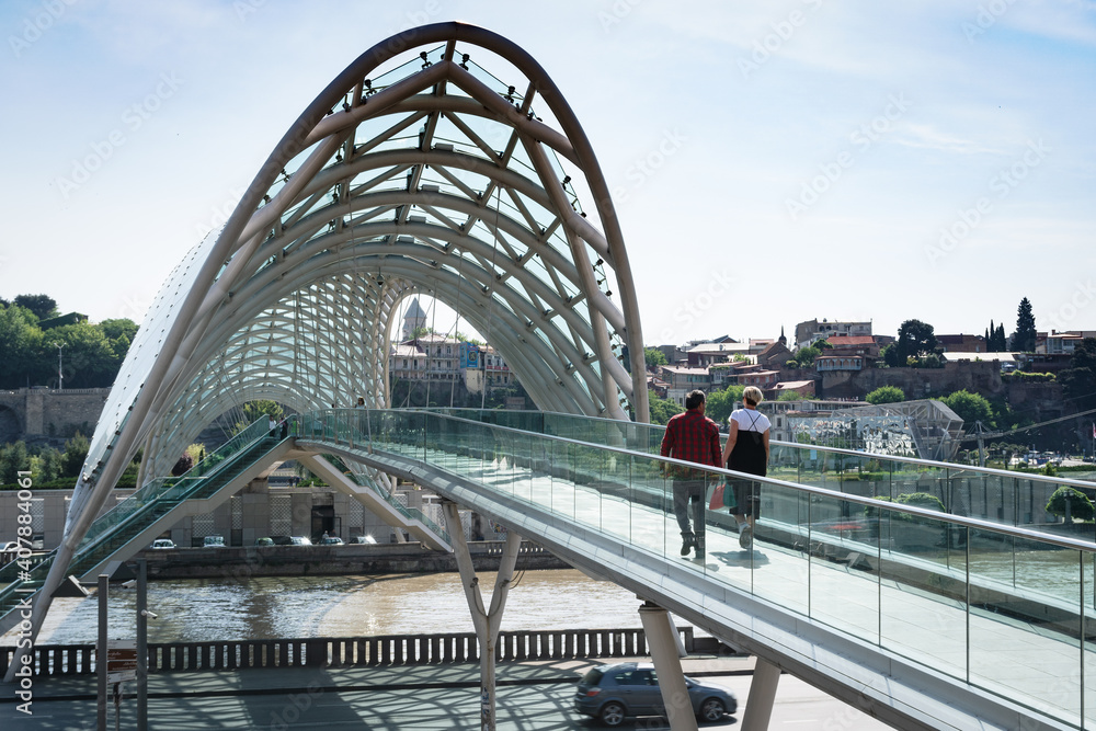 Obraz premium Couple crossing the Bridge of Peace over Kura River (Mtkvari) in Tbilisi, Georgia.