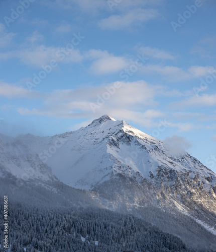 Snow covered mountains and forest blue skies