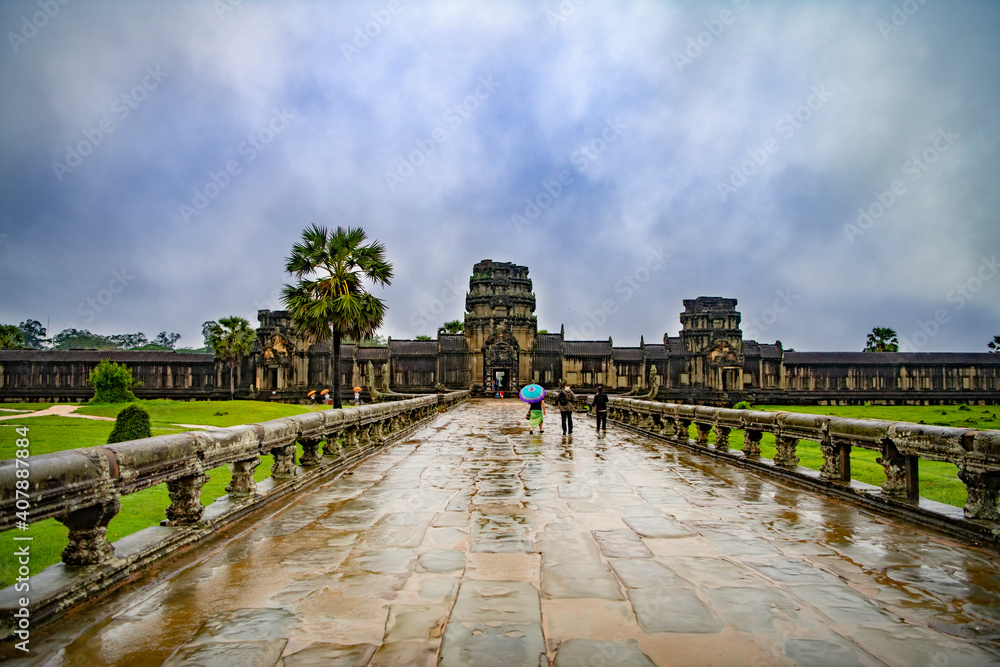 Fototapeta premium Angkor Wat-largest temple in the world. It is raining. Tourists walk around the temple
